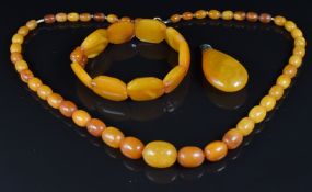An amber necklace of 47 oval beads, amber bracelet and faux amber pendant
