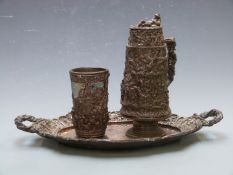 19thC continental plated jug, beaker and tray with repoussé decoration of dancing, drinking and