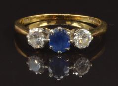 An 18ct gold ring set with an oval cut sapphire of approximately 0.4ct and two diamonds, each