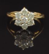 An 18ct gold ring set with seven round cut diamonds in a flower cluster, total diamond weight