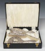 Cased hallmarked silver four piece dressing table set with embossed decoration
