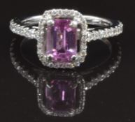 An 18ct white gold ring set with an emerald cut natural pink sapphire surrounded by diamonds, with