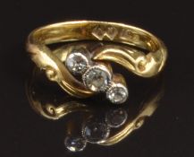 An 18ct gold ring set with three diamonds in a scrolling twist setting, size G, 2.7g