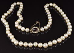 A single strand necklace of cultured pearls, the 9ct gold clasp set with a garnet and split pearls