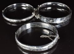 Three silver bangles with engraved decoration, one by Liberty & Co