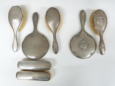 Two hallmarked silver dressing table sets, one comprising hand mirror and two pairs of brushes,