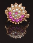 A yellow metal ring set with round cut rubies and seed pearls in a cluster, size K, 4.3g