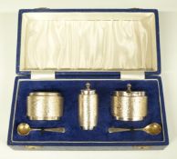 Cased retro three piece hallmarked silver cruet set with bark effect decoration and blue glass