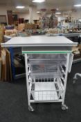 A metal medical trolley with two plastic trays and adjustable shelf and wire mesh basket