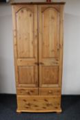 A pine double door wardrobe fitted with three drawers