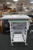 A metal medical trolley with two plastic trays and adjustable shelf and wire mesh basket