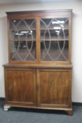 A Regency glazed mahogany double door bookcase fitted with cupboard beneath on bracket feet
