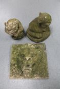 A weathered concrete lion mask plaque together with two garden figures of a gargoyle and a cat