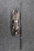A carved African tribal mask together with a spear