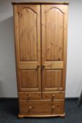 A pine double door wardrobe fitted with three drawers