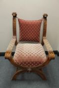 A heavily carved walnut X-framed armchair in pink dralon