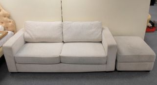 A large two seater settee and matching footstool in cream speckled fabric