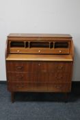 A mid 20th century teak barrel fronted bureau