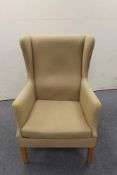 A mid 20th century wingback armchair in sand colour fabric