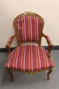 A carved French walnut and gilt salon armchair in striped fabric
