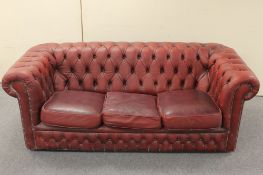 A red buttoned leather three seater Chesterfield settee