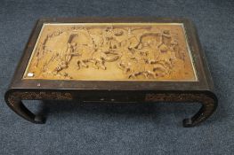 A carved hardwood Chinese coffee table with frieze panel top depicting a battle scene