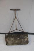 An antique concrete garden roller with cast iron handle