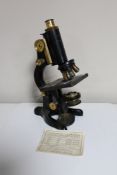 An early 20th century microscope, black metal and brass, stamped 