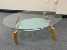 An oval glass topped coffee table on metal and wooden legs
