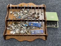 A wooden spoon rack containing a large quantity of continental silver and plated crested teaspoons