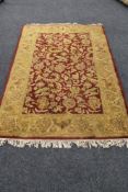 A fringed floral woolen rug on red ground.