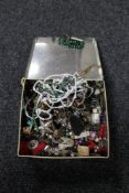 A tin of beaded necklaces, enamel badges,