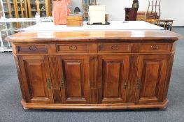A contemporary walnut four drawer sideboard on bun feet