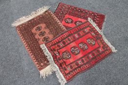 Three fringed woolen Persian hearth rugs on red ground
