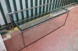 A rectangular glass topped coffee table on chrome base