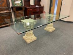 A contemporary glass topped twin pedestal dining table on Corinthian style columns,