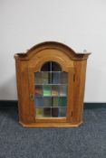 A blonde oak hanging corner cabinet