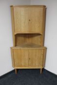 A blonde oak double door corner cabinet