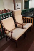 A mid century teak armchair and fireside chair in beige fabric