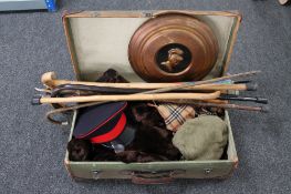 A vintage suitcase containing various clothing, walking sticks,