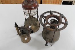An antique blow torch together with a swing handled lamp and a burner