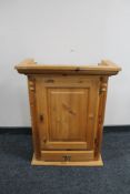A pine wall cabinet fitted with a drawer