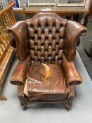 A distressed buttoned brown leather Chesterfield armchair