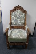 A heavily carved oak armchair with floral tapestry covering