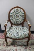 A carved walnut armchair with floral tapestry covering