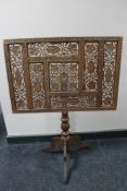 A carved fret work fire screen on tripod base