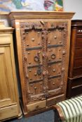 A uniquely carved oak cabinet with metal adornments