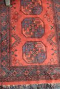 An Afghan Bokhara rug on red ground,