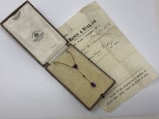 An antique gold two stone amethyst and pearl pendant on a gold chain,