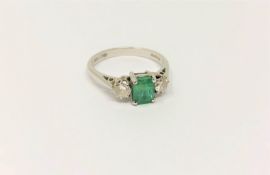 An 18ct white gold two stone diamond and emerald ring, size M/N, 3.2g.